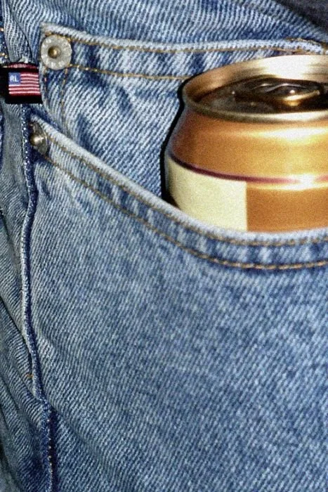 A can partially tucked into the pocket of blue denim jeans.