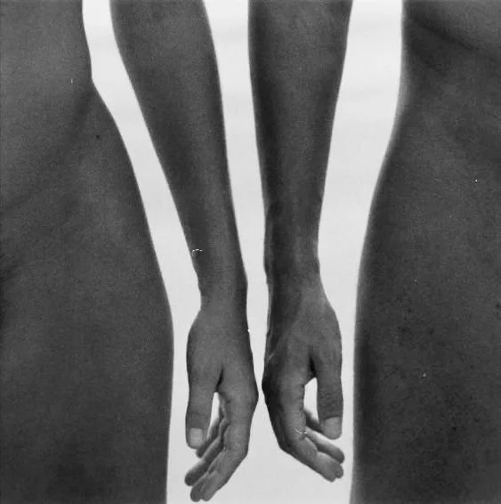 black and white photo of two nude figures standing with arms outstretched