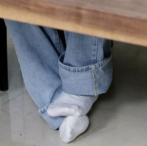 person wearing jeans and white socks sitting cross-legged