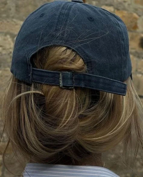 Person wearing cap backwards with hair pulled through opening