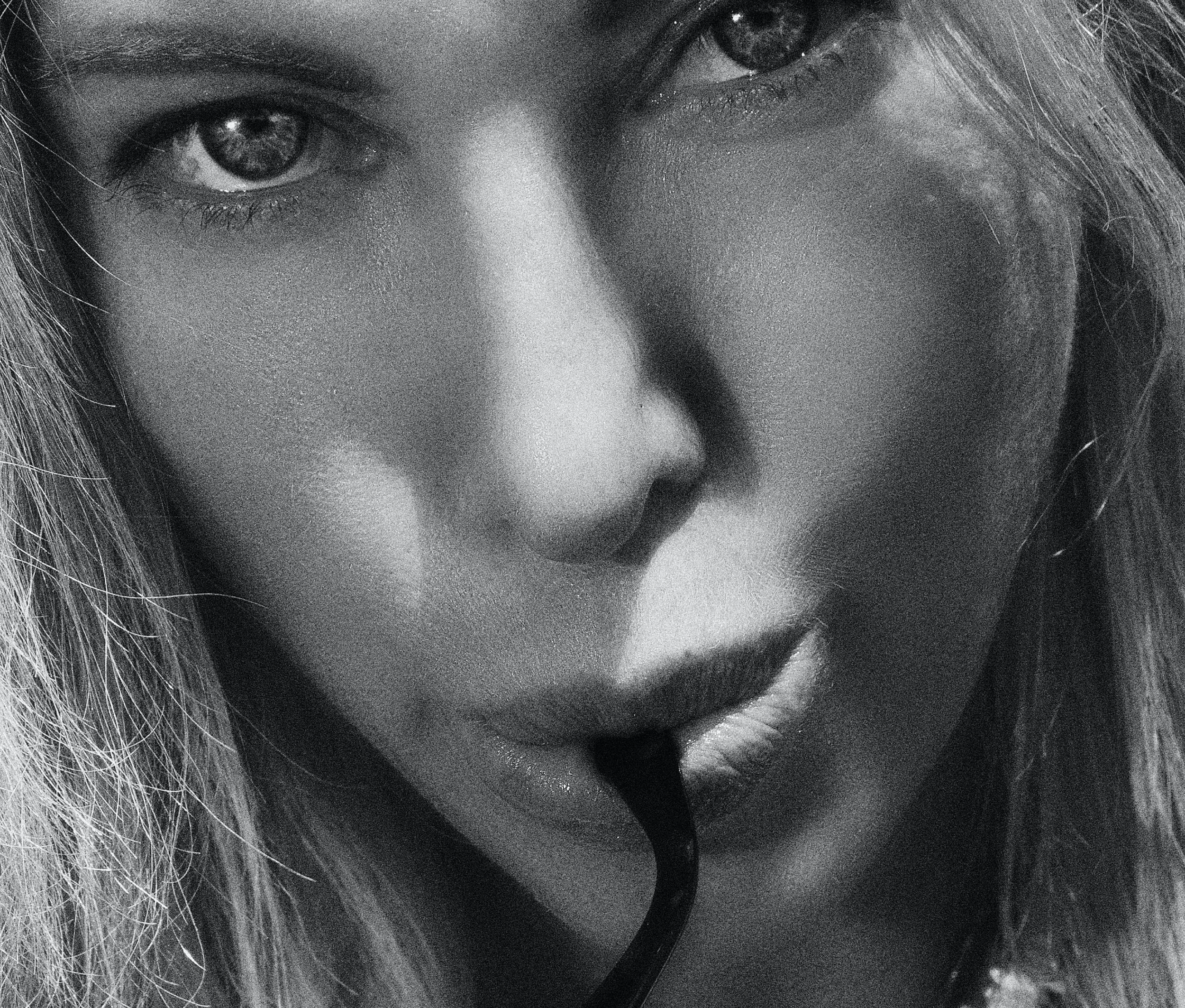 Black and white close-up of a person sipping through a straw, with a focus on the eyes and lips.
