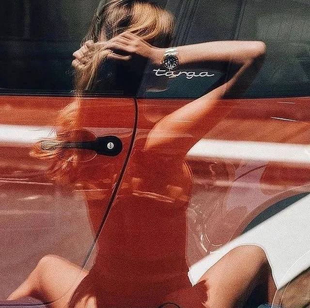 Reflection of a woman on the car window with Porsche Targa badge