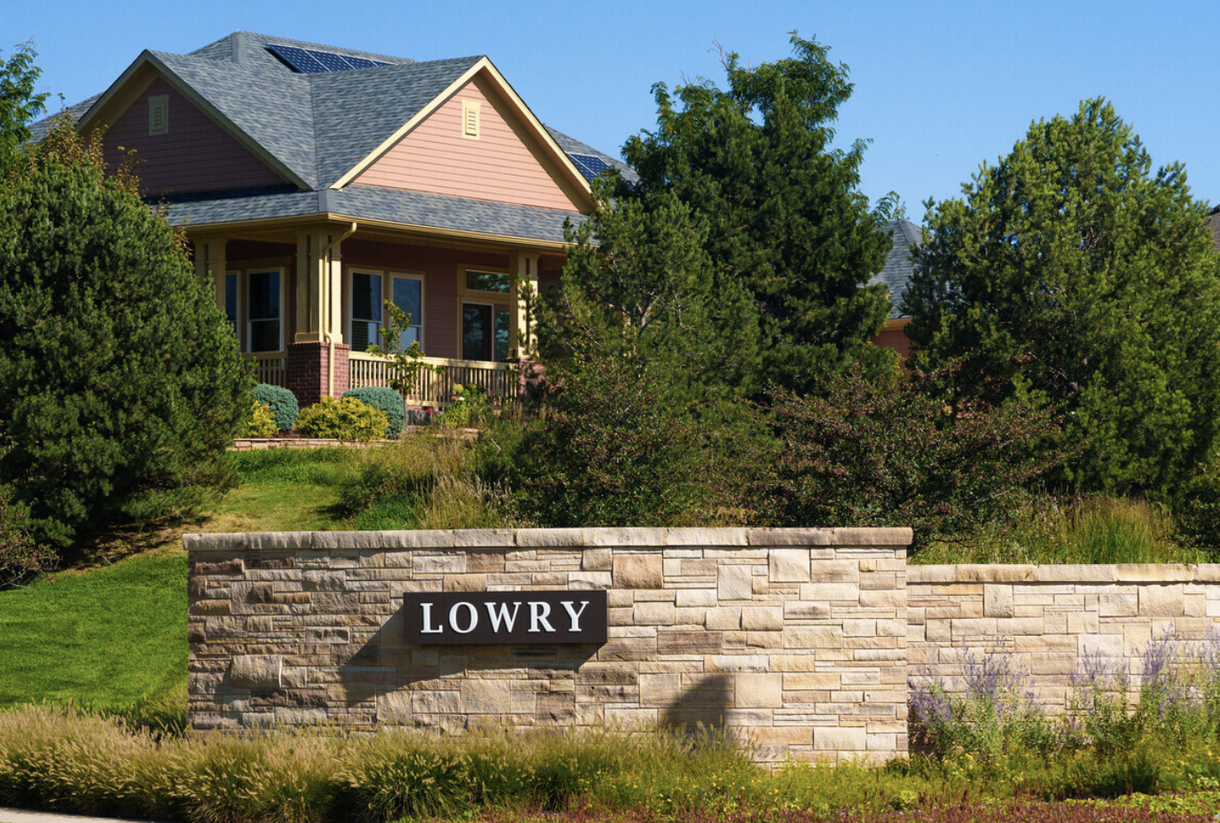 Stone sign with "LOWRY" in front of a house surrounded by trees and greenery.