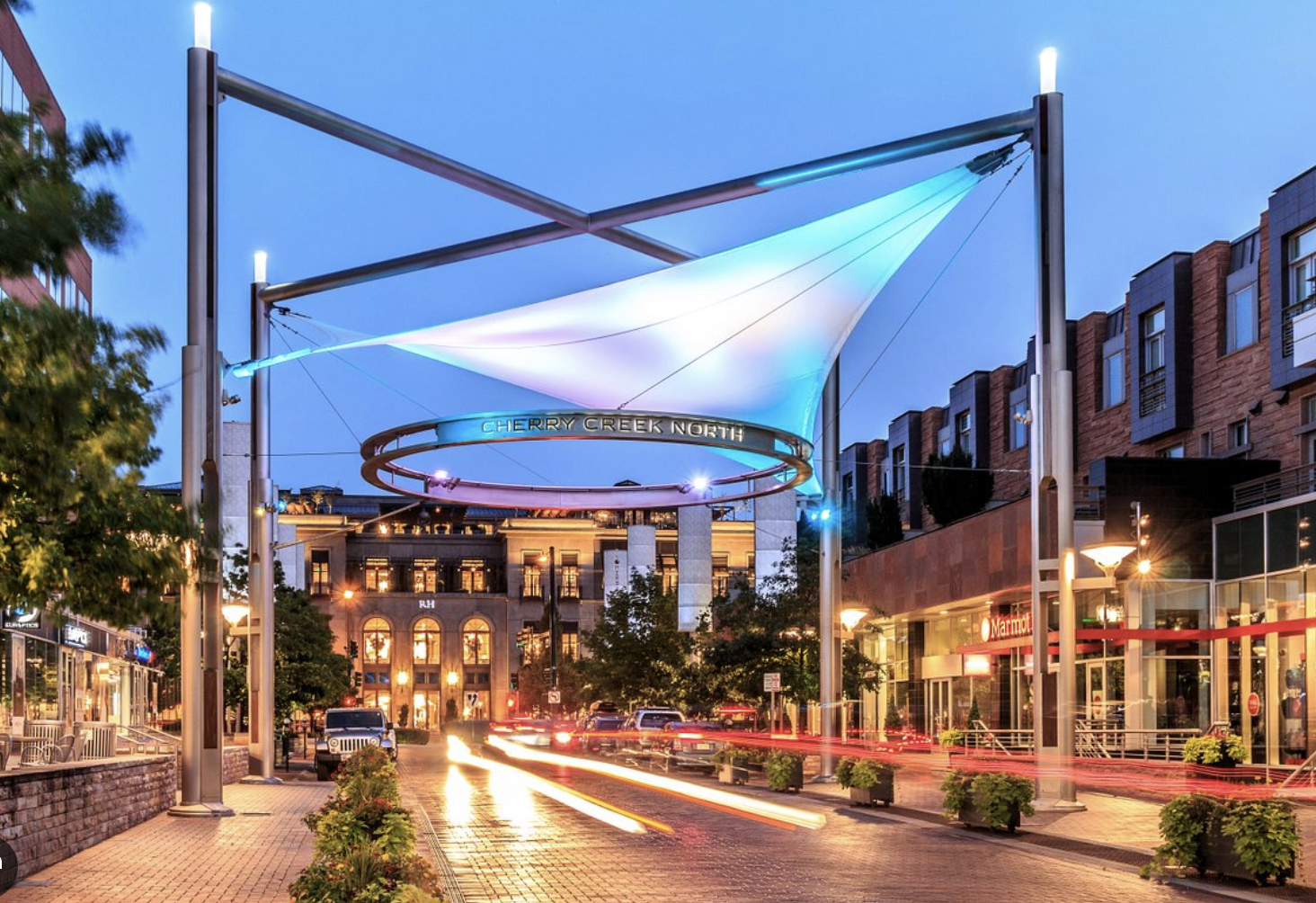 Cherry Creek North shopping district at dusk with illuminated canopy and storefronts.