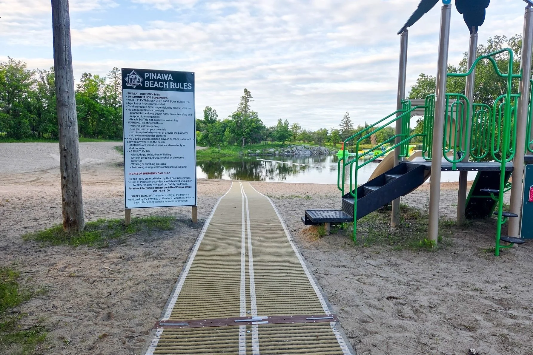 Pinawa Public Beach showcasing the accessibility mat, play structure, and the water