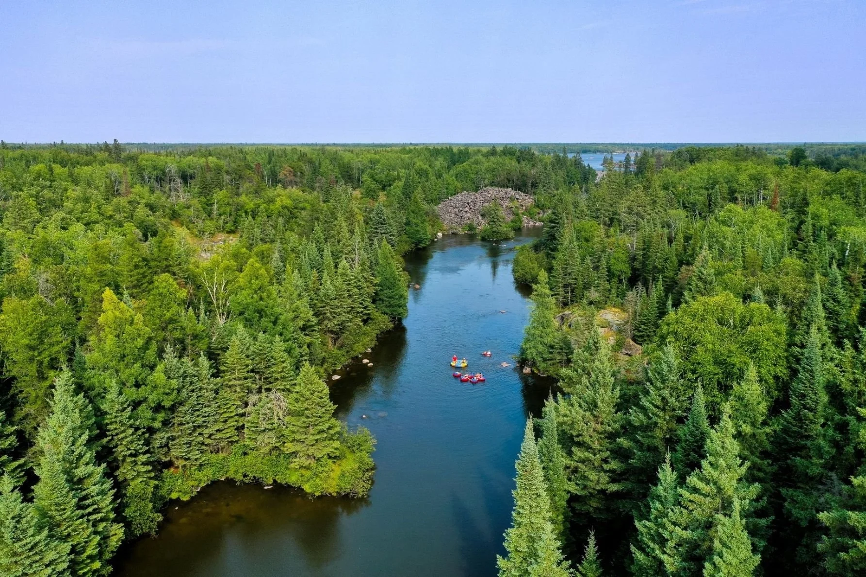 Drone photo of the Pinawa Channel with people floating on tubes highlighting this classic Winnipeg River, Manitoba, activity.