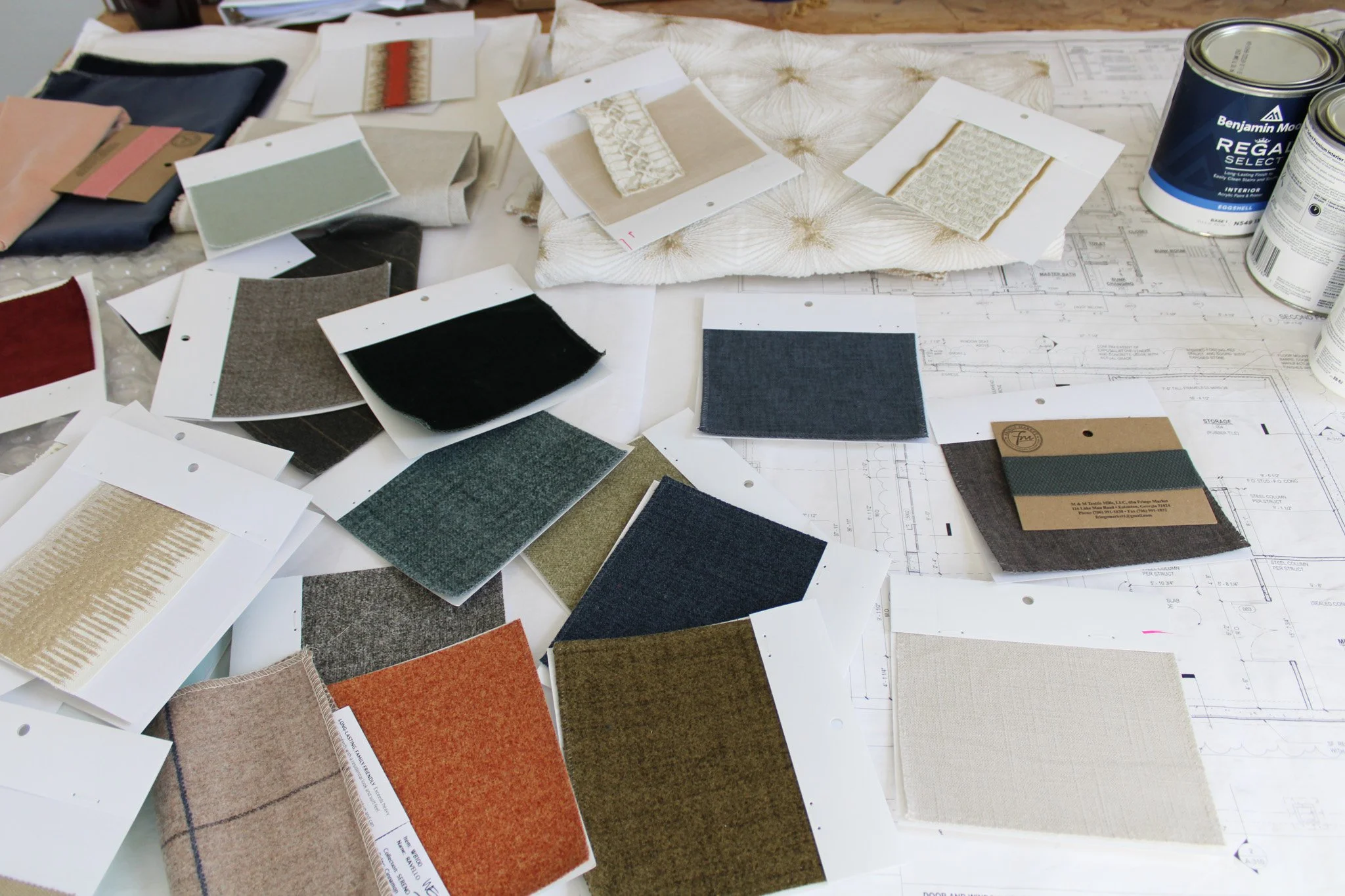 Fabric samples and a paint swatch arranged over an architectural blueprint, representing the preparation and planning that goes into a U-Fab Interiors in-home design consultation.