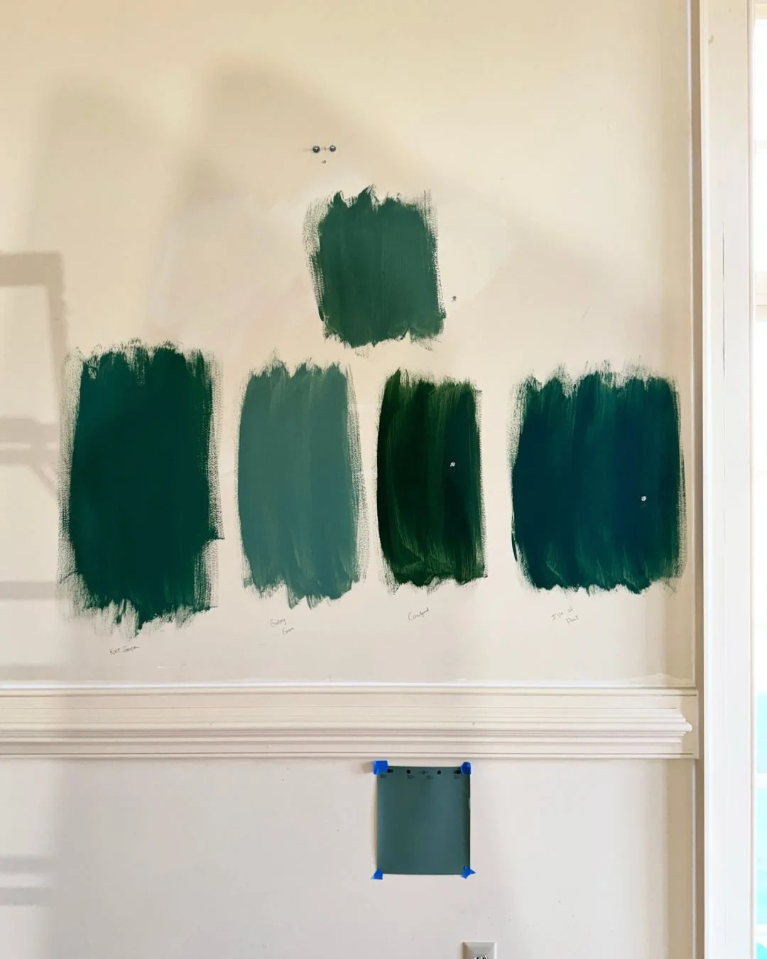Multiple Benjamin Moore and Sherwin WIlliams paint swatches tested on the wall during the color selection process for the Foundry Manor show house Dining/Living Room.