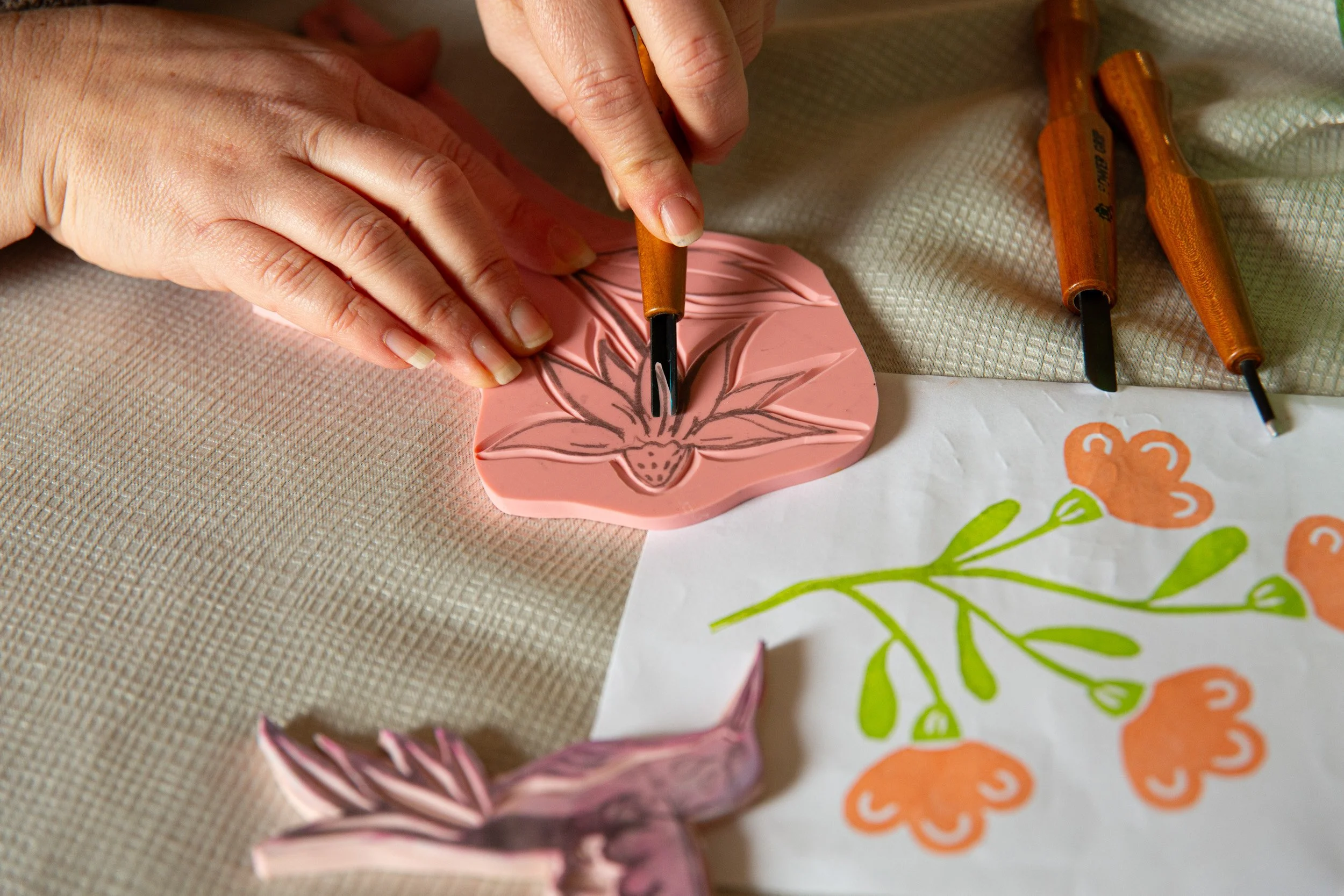 Hands carving a floral printing block for handmade products at Wondering Time in Skippack, Pennsylvania.