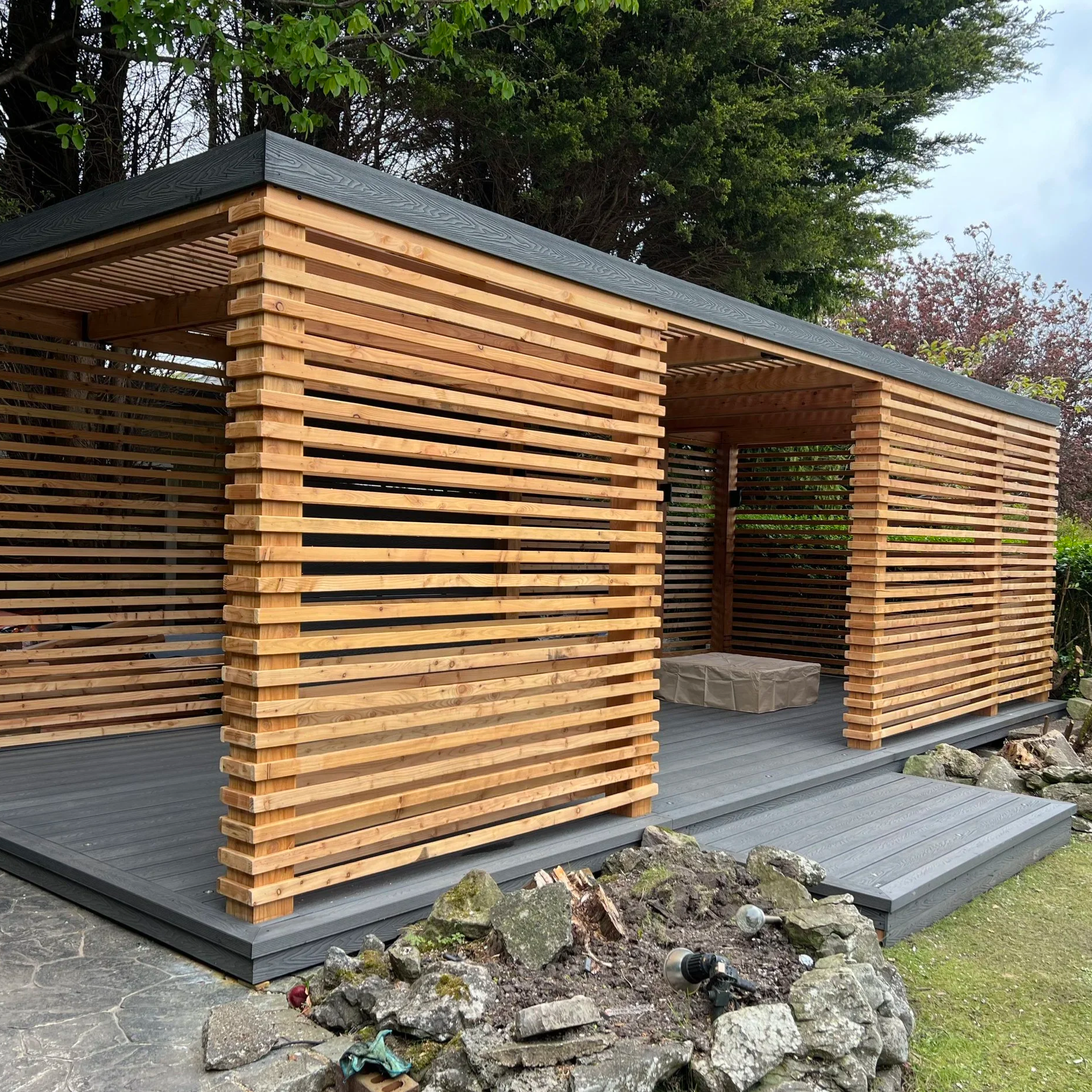 Bespoke timber garden pergola with contemporary slatted screens, composite decking and covered outdoor seating area