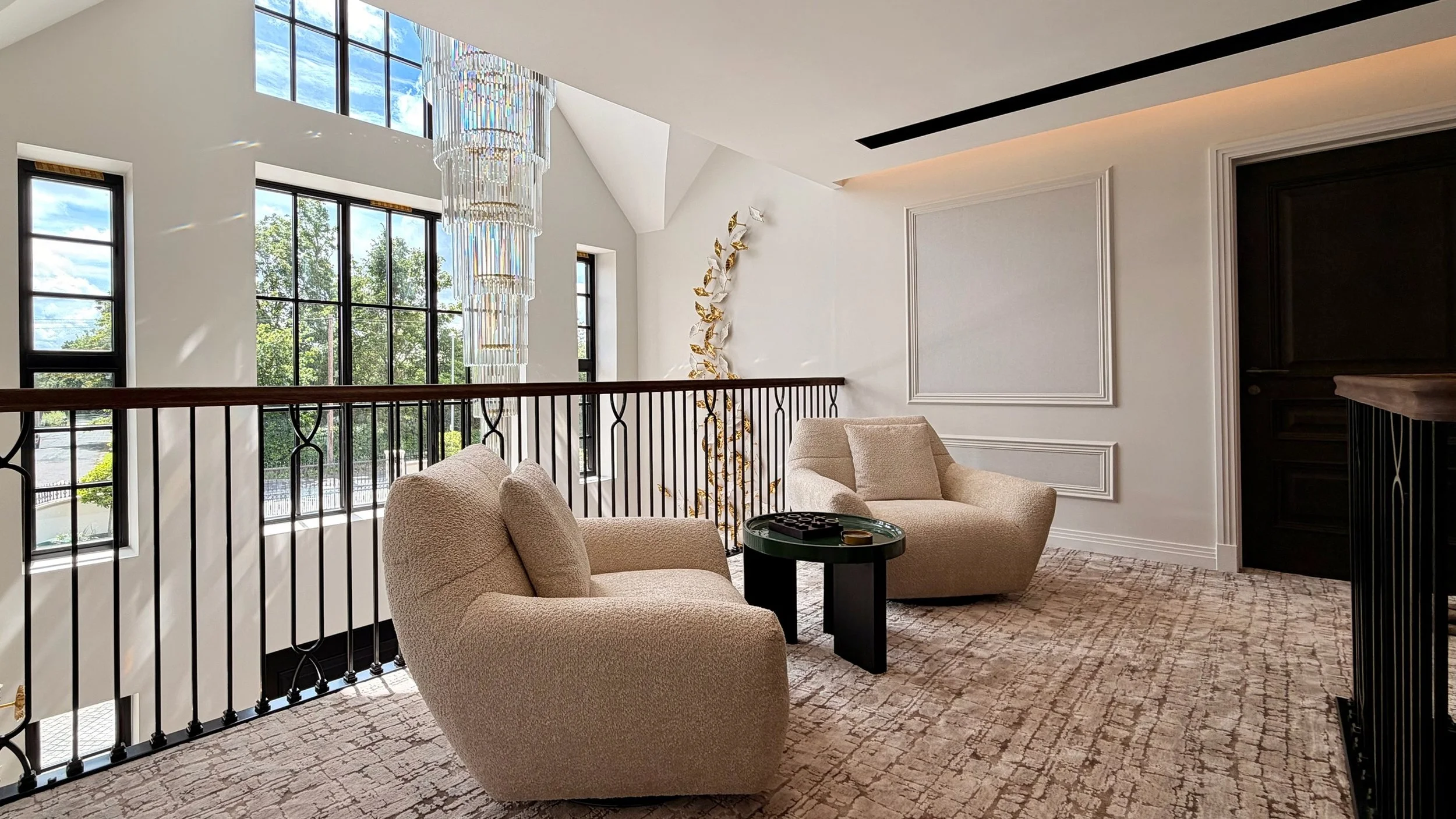 Elegant galleried landing combining architectural glazing, statement lighting and refined interior design within a contemporary residence.