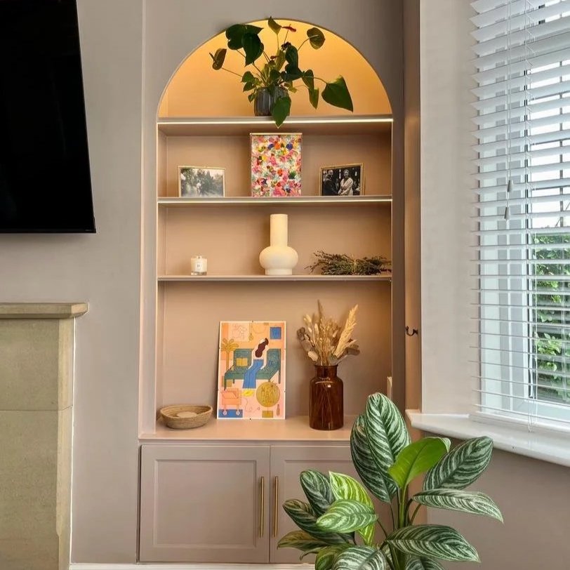 Bespoke alcove cabinetry with arched illuminated shelving, integrated storage and a feature fireplace in a contemporary living room