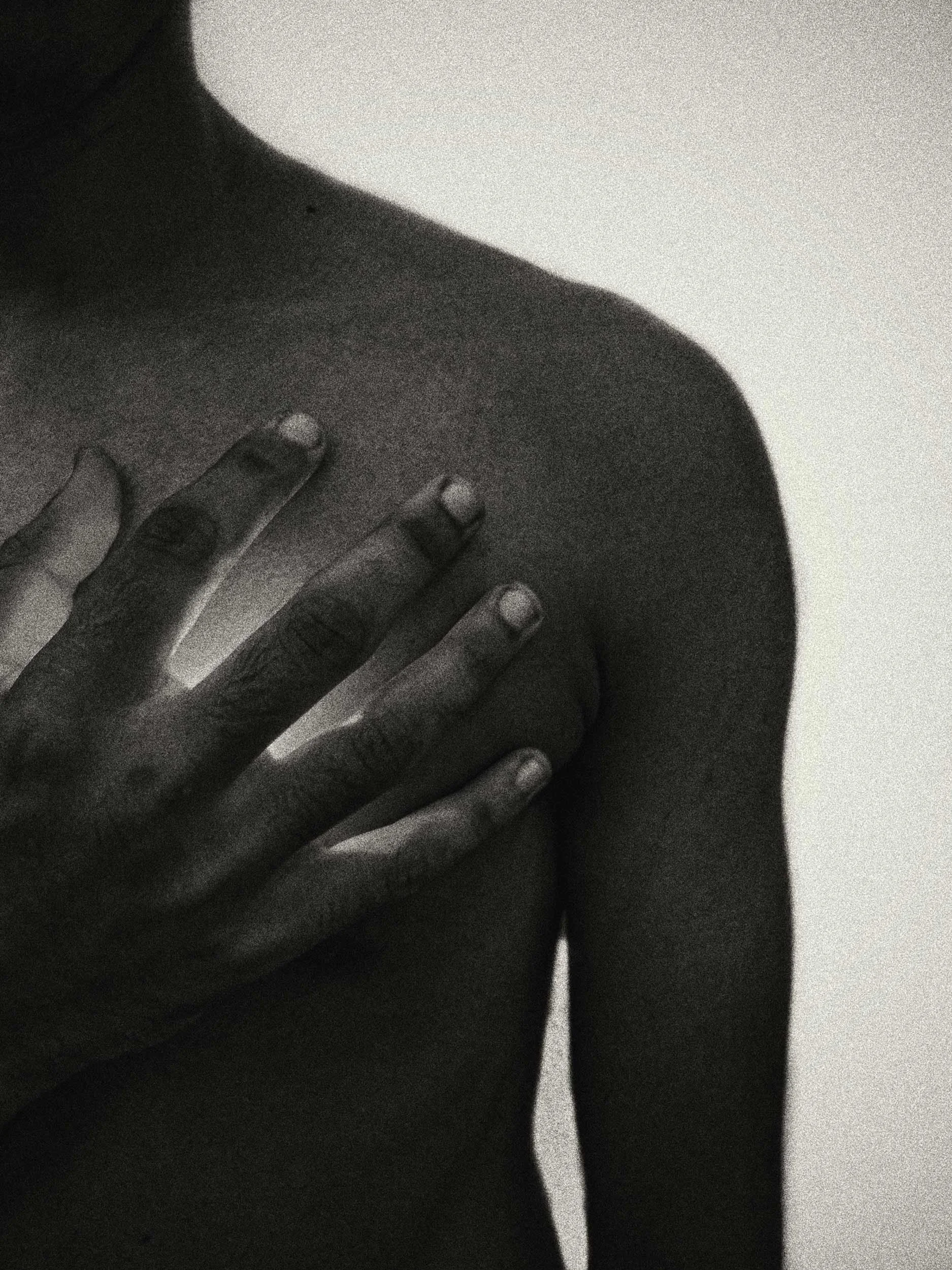 A black and white photo of a person holding their hand against their heart