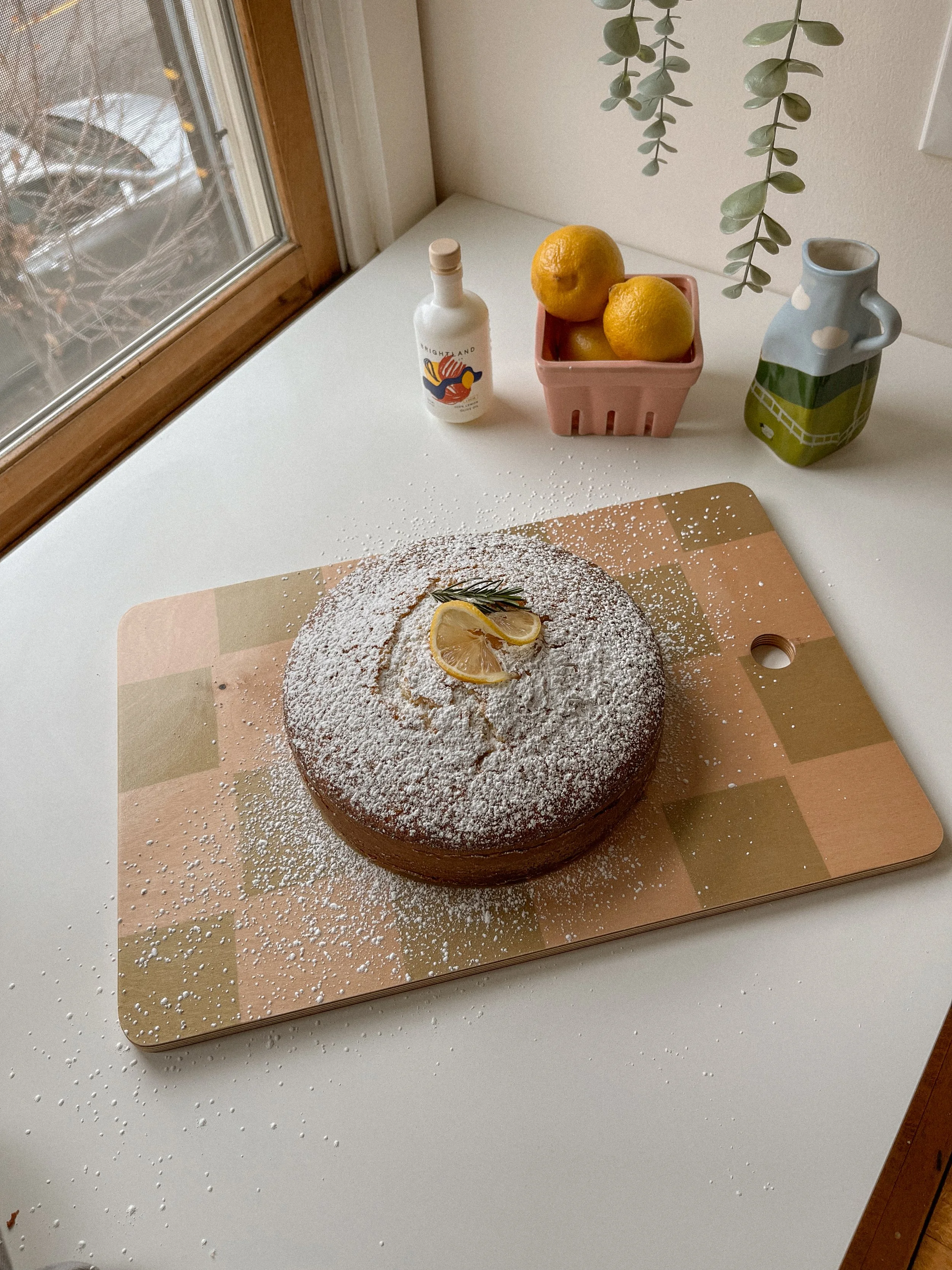 plate of olive oil cake dusted with powdered sugar, and decorated with a thin slice of lemon