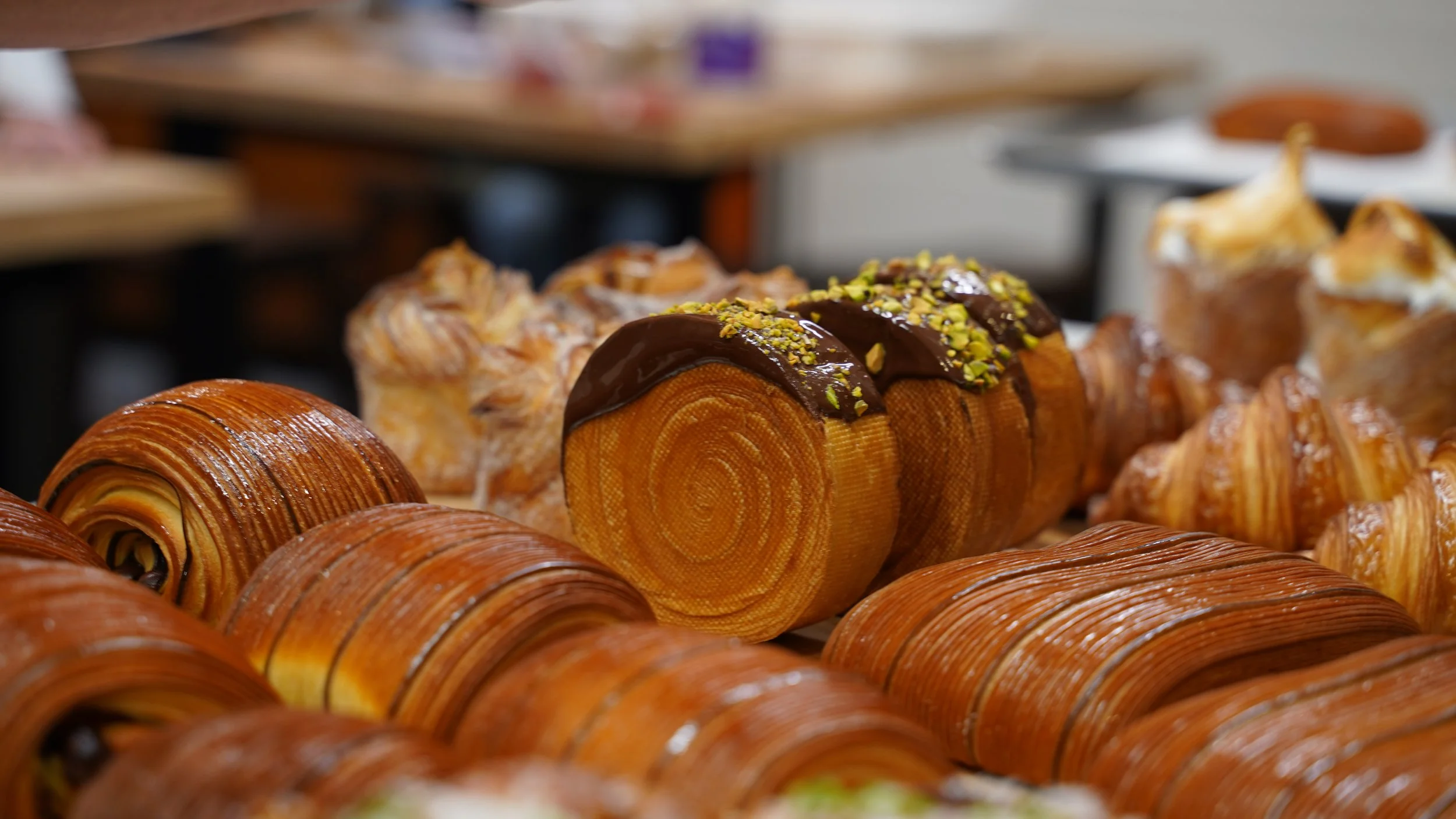 a spread of laminated pastry including pain Suisse, cruffins, new York rolls, cross laminated pain au chocolat
