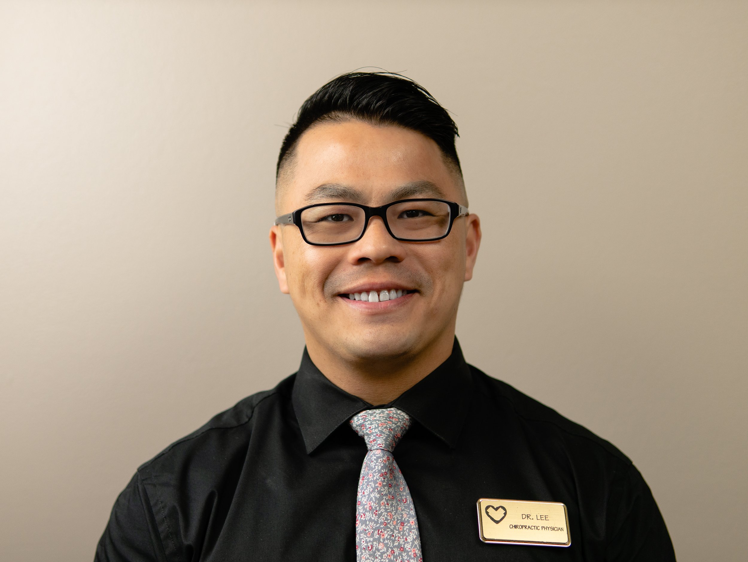 Smiling person wearing glasses and a black shirt with a name tag.