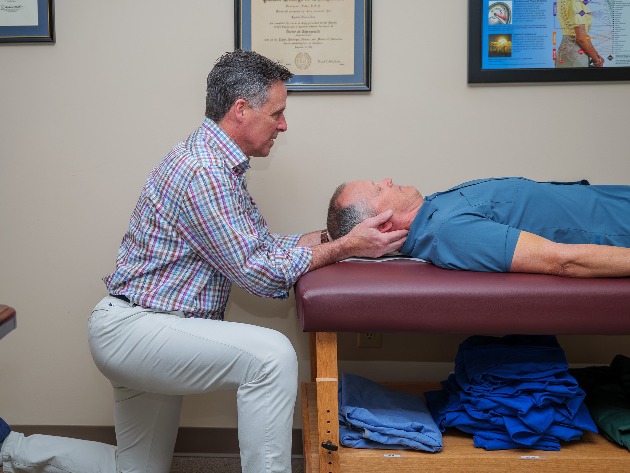Chiropractor performing neck adjustment on a patient lying on a treatment table.