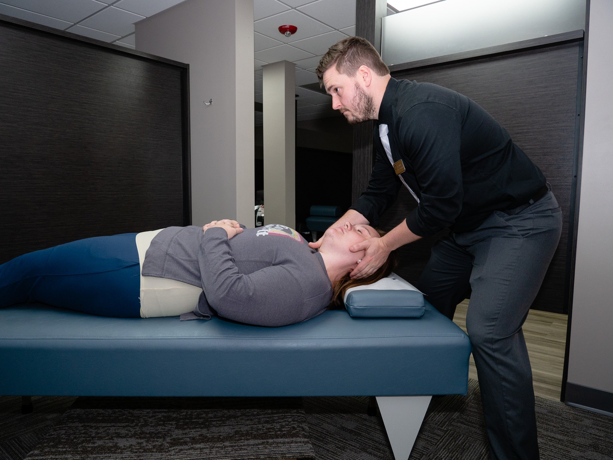 Chiropractor performing neck adjustment on patient lying on table in clinic
