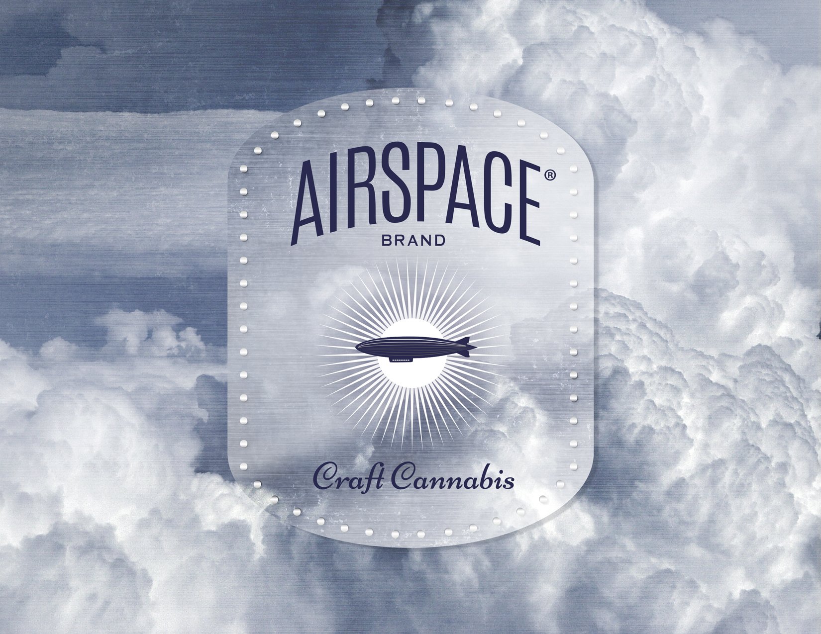 A sign with the words 'AIRSPACE BRAND' at the top, a graphic of a blimp with a sunburst behind it in the middle, and the phrase 'Craft Cannabis' at the bottom, set against a background of cloudy sky.