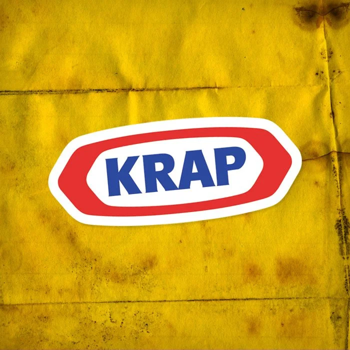 Sticker with the word "KRAP" in bold blue letters on a white background, outlined in red, on a yellow, weathered surface.