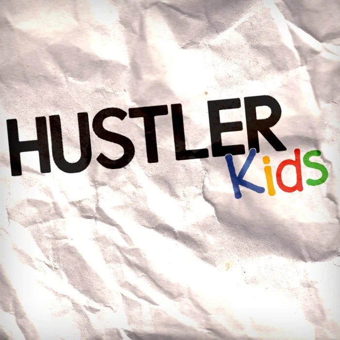 Crumpled piece of paper with the words "HUSTLER Kids" printed on it, with "HUSTLER" in black and "Kids" in colorful letters.
