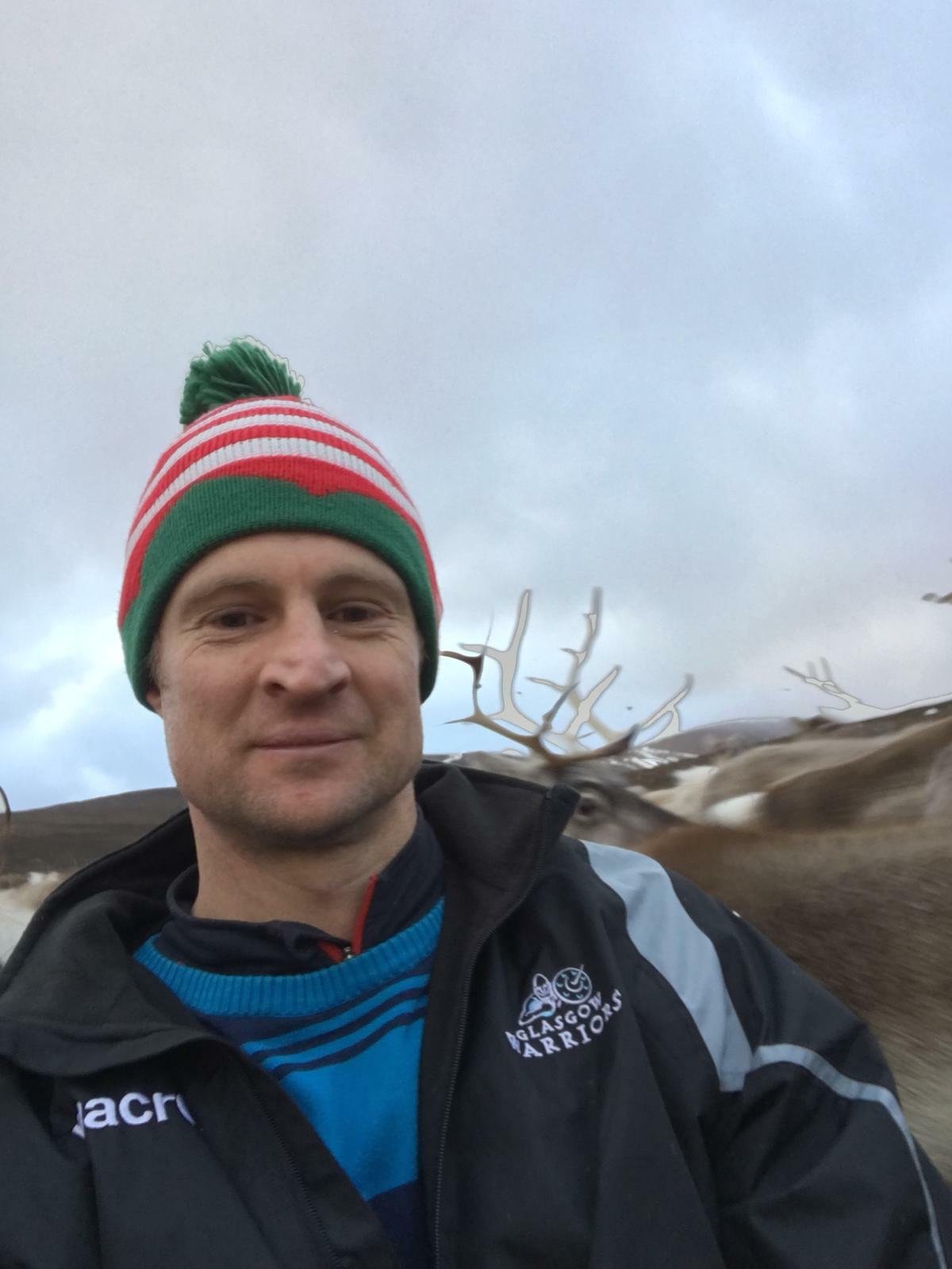 Alastair is close to the camera with reindeer in the background