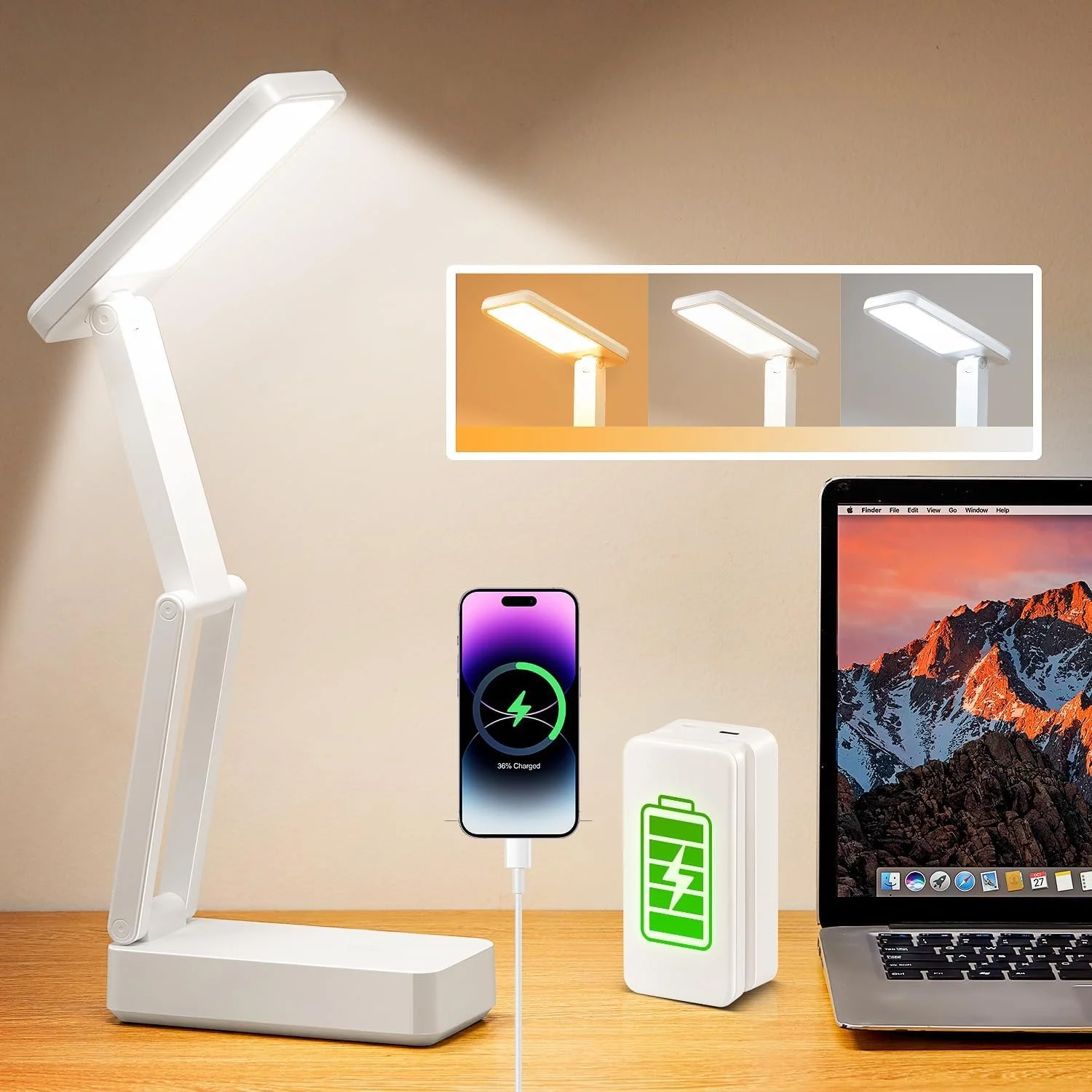 A desk lamp with adjustable arm turned on, a smartphone charging with 36% battery, a portable battery pack with a green charging icon, and a laptop with a mountain desktop background.