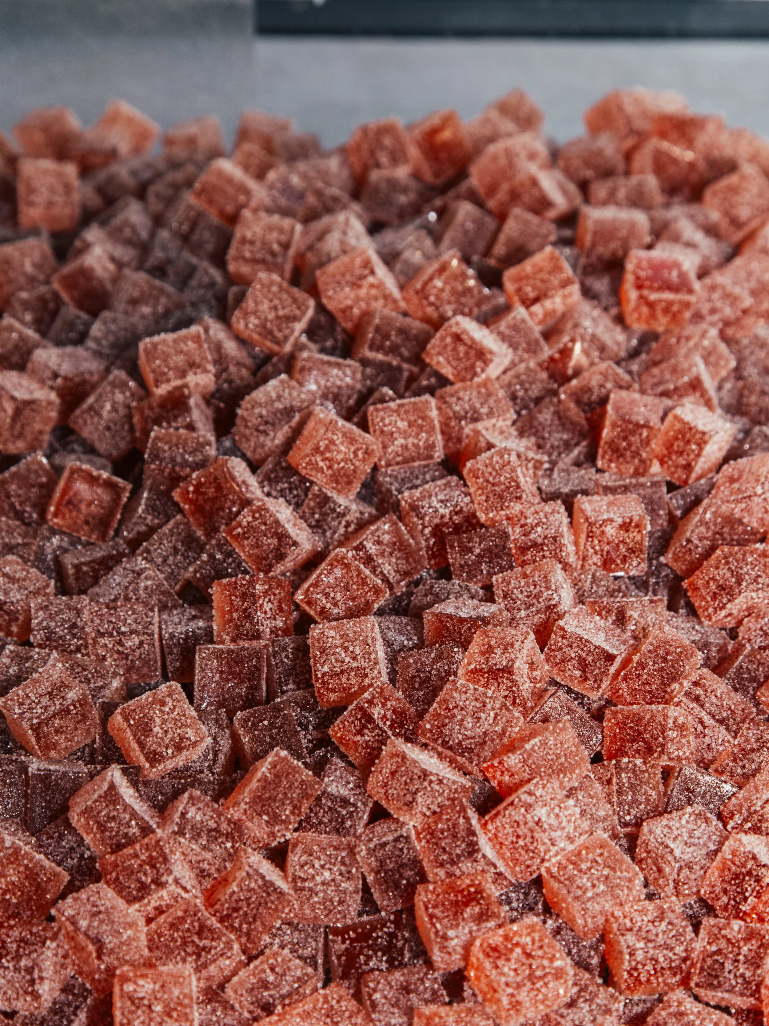 Close-up view of sugar-coated red and brown gelatin cubes or candies.