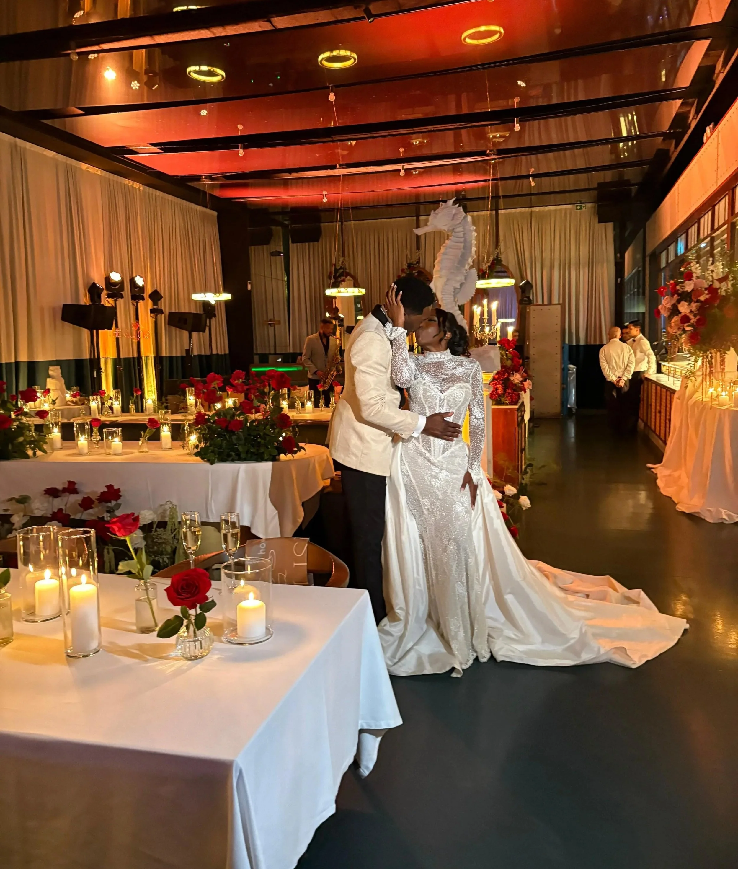 A bride and groom share a kiss during their wedding reception in a decorated banquet hall with candles, roses.Vogue-Inspired Luxury Wedding Design in Portugal