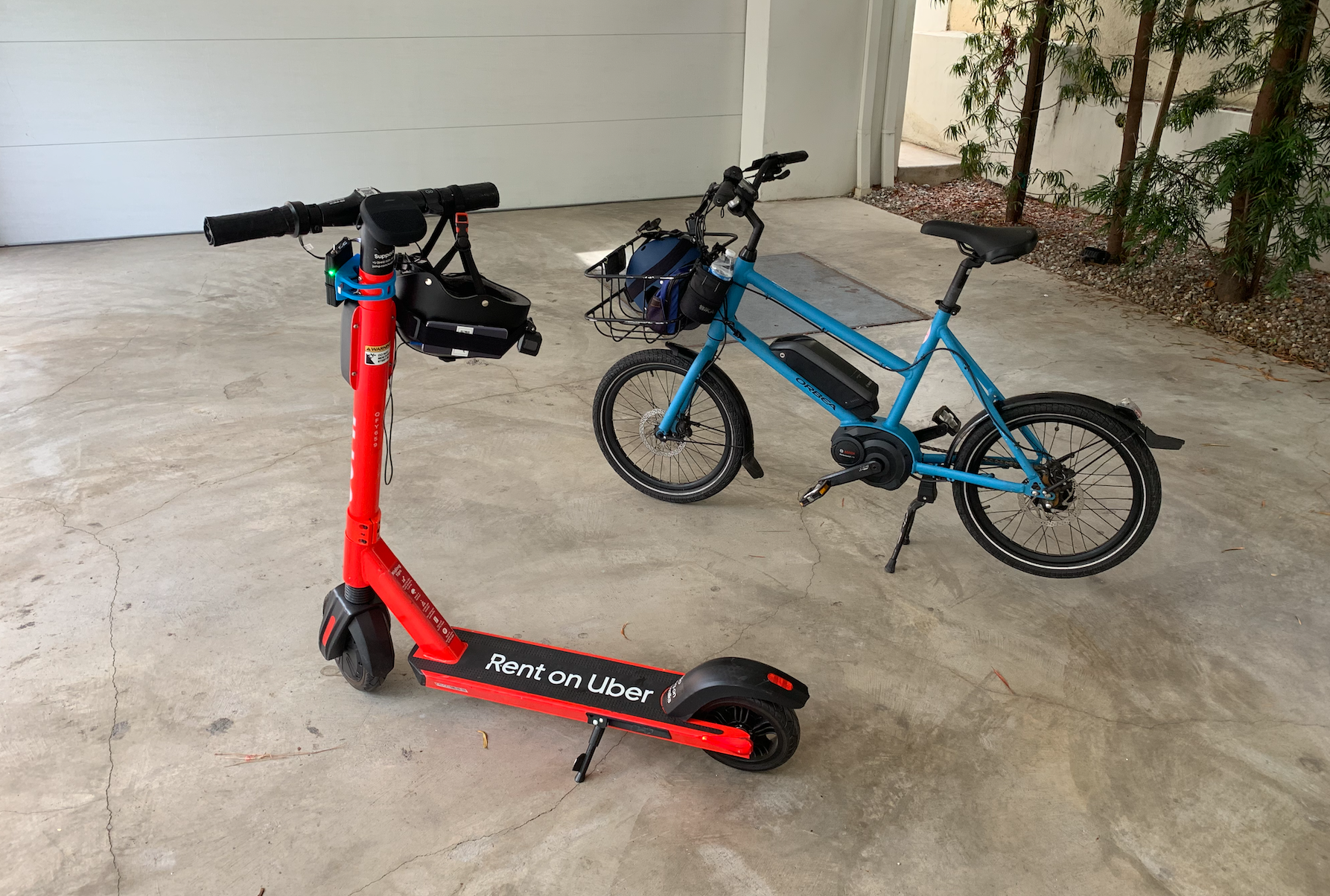 A red electric scooter next to a blue electric bike parked in a garage