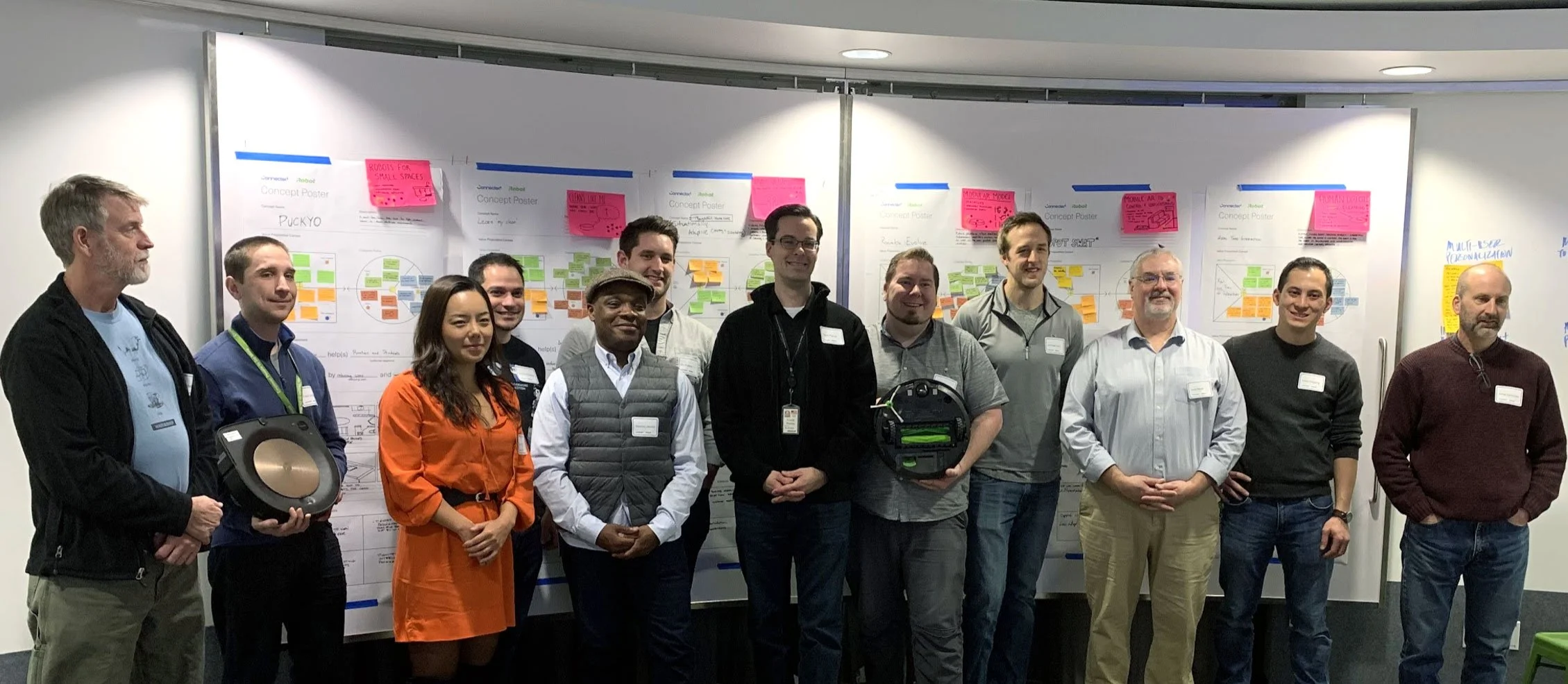 A group of people posing in front of concept posters with sticky notes