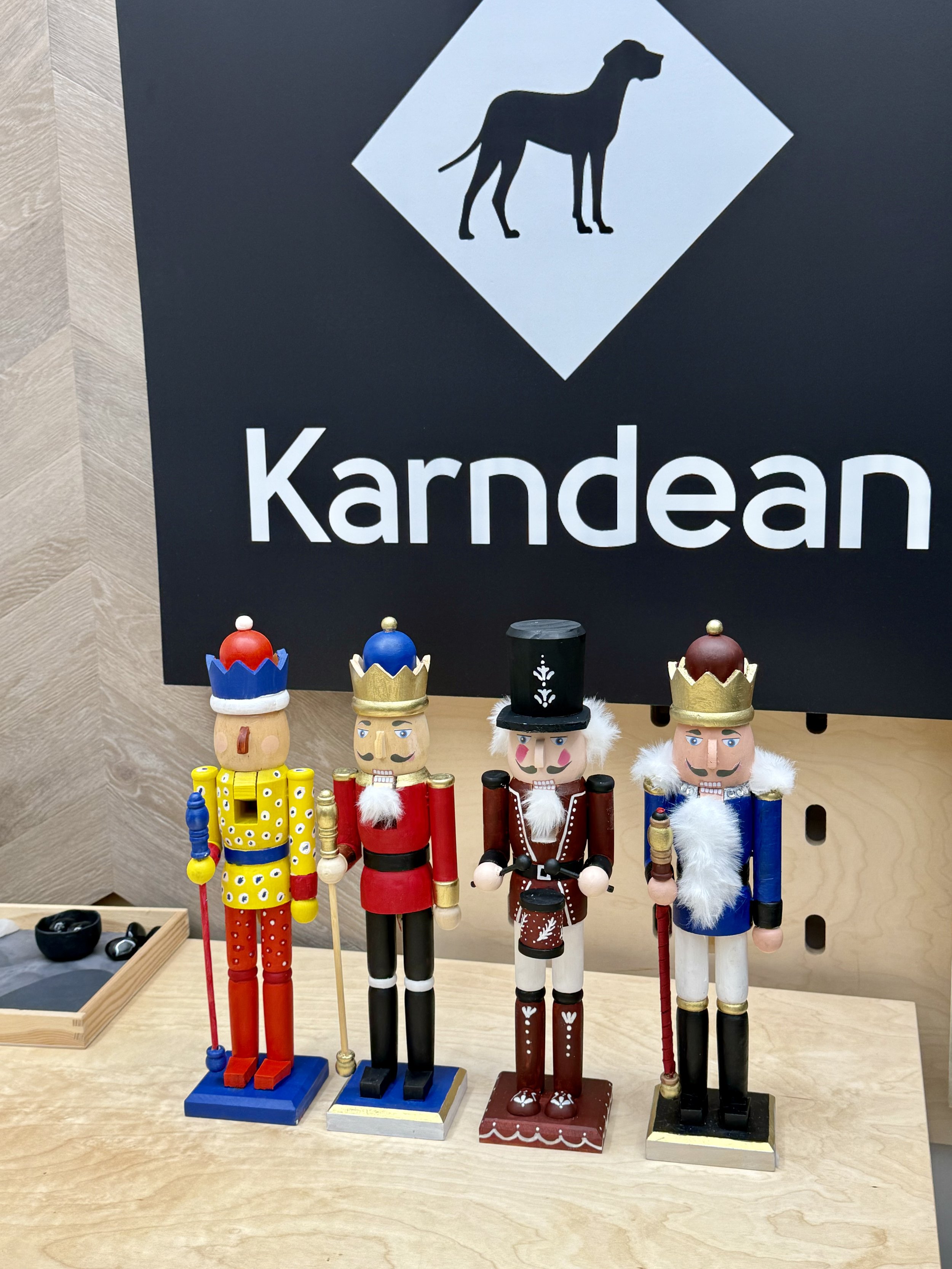 Four nutcracker figurines placed on a wooden surface in front of a sign that reads 'Kardean' with a dog silhouette logo.