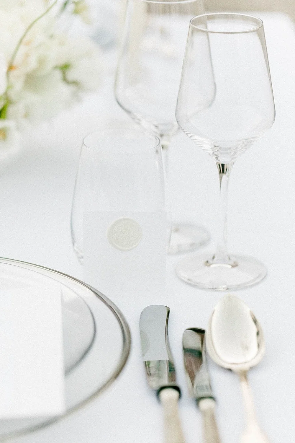 Weiße Tischdeko zur Hochzeit mit Platzteller mit silbernem Rand, Kristallgläsern und silbernem Besteck von de Waay als eleganter Kontrast