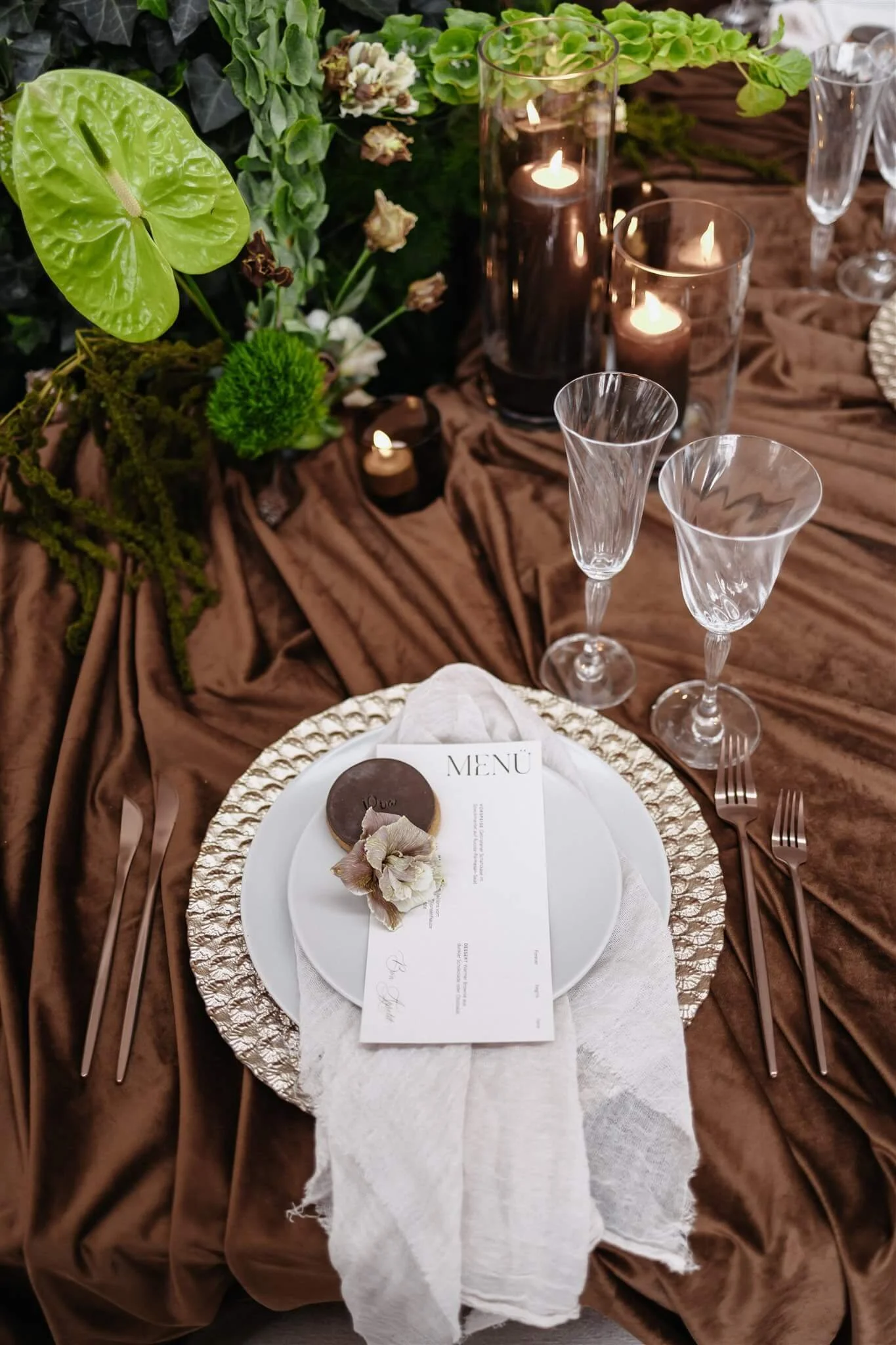 Gedeckter Hochzeitstisch mit Platzteller in Mocha Mousse, Menükarte und Leinenserviette in warmen Brauntönen, Samttischdecke in Braun, Kupferbesteck und Kristallgläsern von de Waay – moderne Tischdeko für Hochzeitsfarben 2026