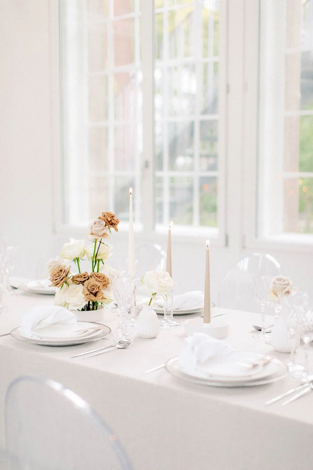 Simple wedding table decor with white table setting, taper candles, crystal glassware and neutral floral arrangement by de Waay