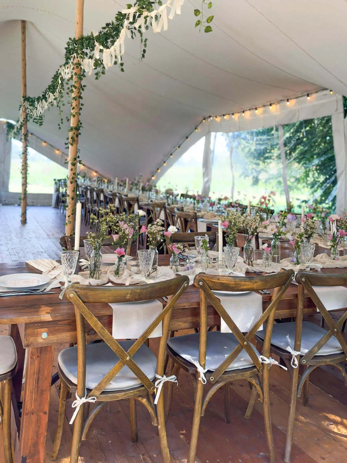 Lange Tafel mit Farmer Tables und Crossback Chairs von de Waay und natürlicher Floristik unter einem Stretchzelt – rustikal-eleganter Earthy Look für eine Zelthochzeit