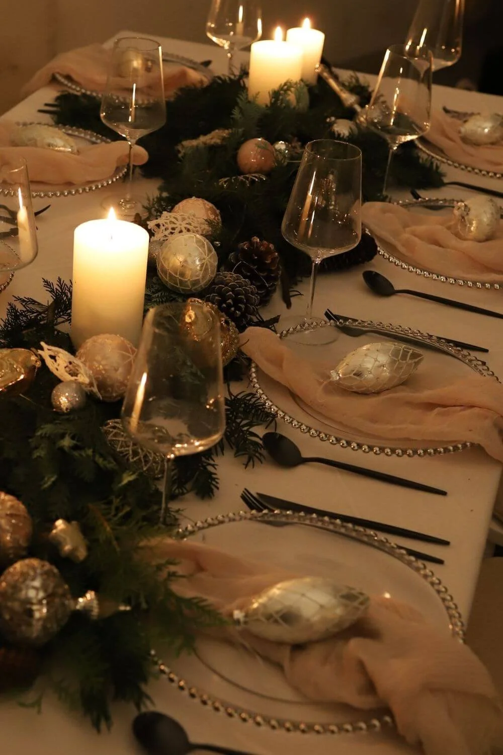 Moderne Weihnachtstafel mit Tannengrün, Kerzen und klarer Tischstruktur – Beispiel für stilvolles, reduziertes Weihnachtsdesign ohne Überladung.