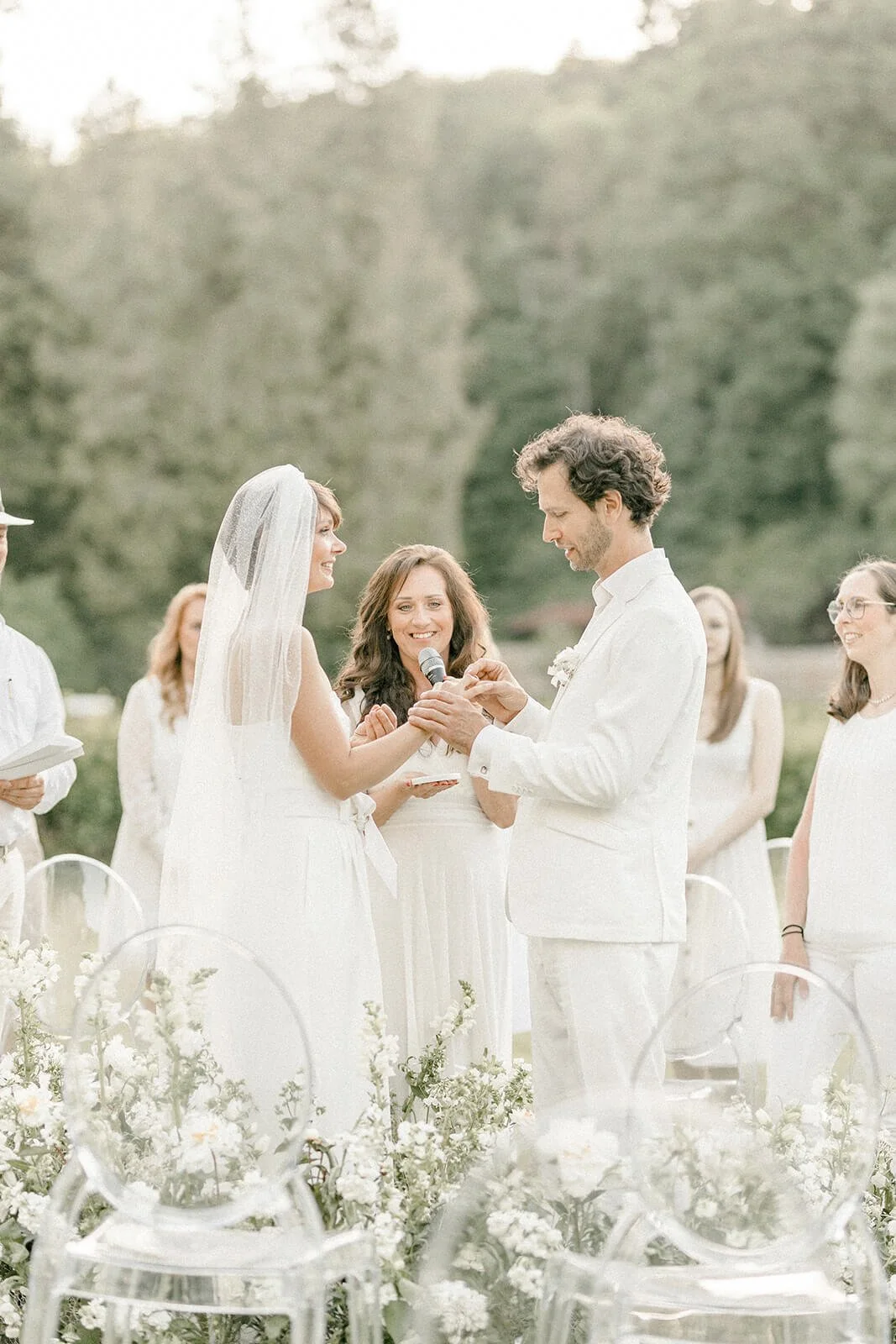 Freie Trauung mit Ghost Chairs von de Waay bei einer Gartenhochzeit im eigenen Garten mit Sitzordnung, Mikrofon und Gästen im Grünen