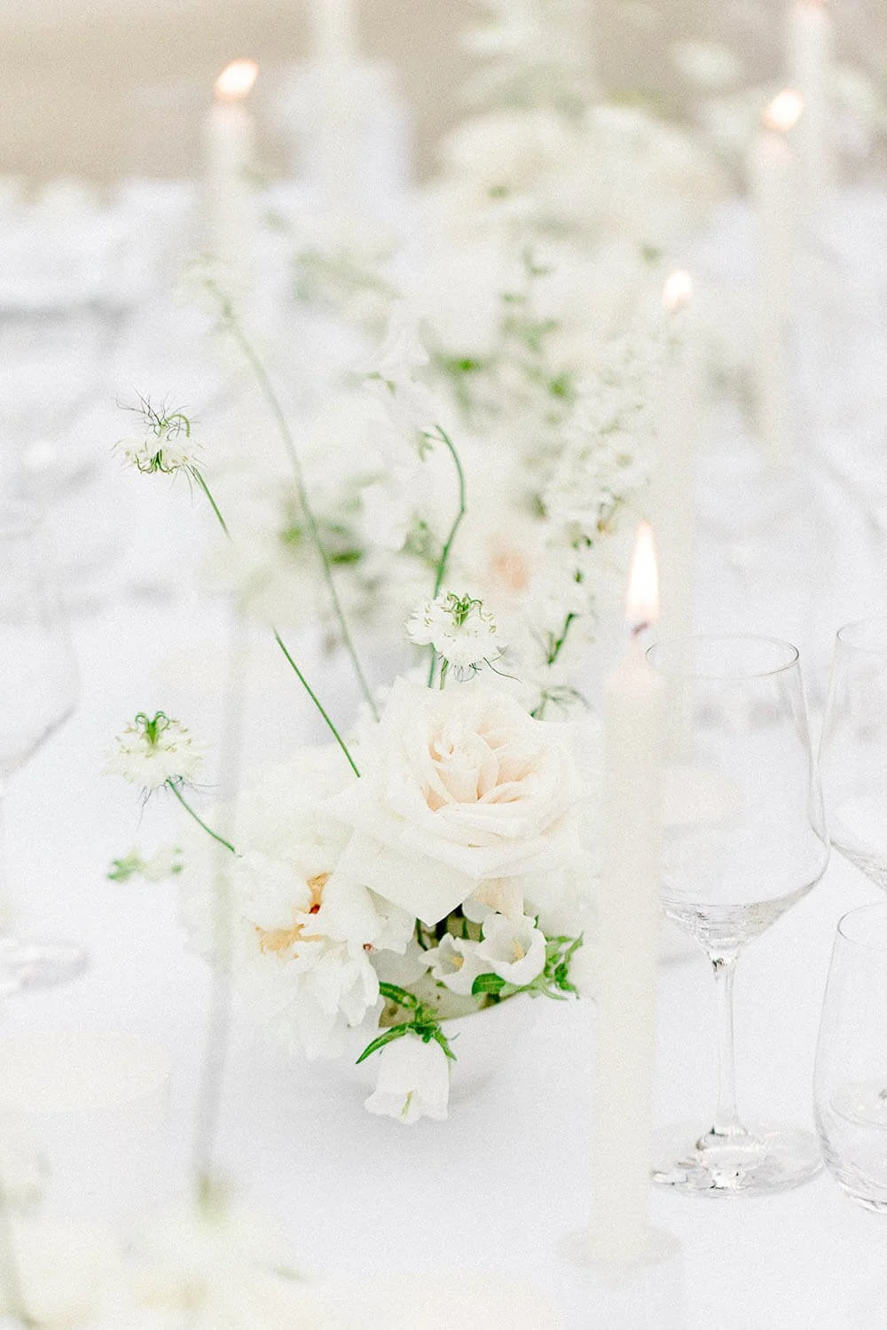 Luftige weiße Blumenkomposition für moderne Tischdeko zur Hochzeit mit Kerzen und feinen Texturen