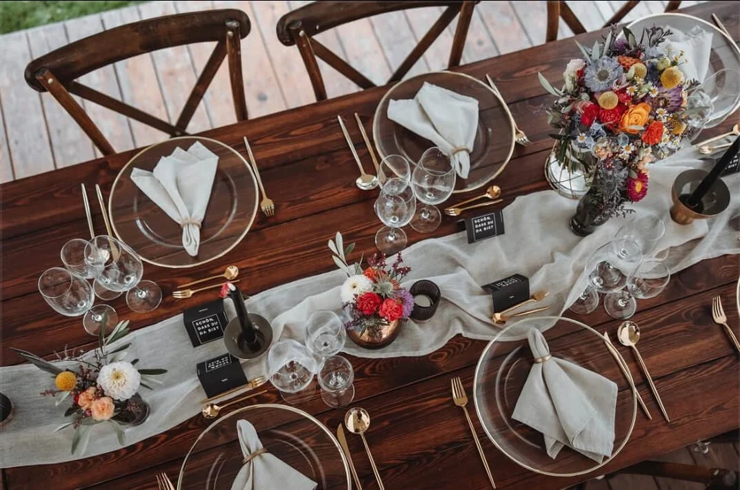 Stilvolle Tischgestaltung mit Holztisch, Crossback-Stühlen und dezenten Details – für Paare, die bei einer Zelthochzeit bewusst gestalten möchten