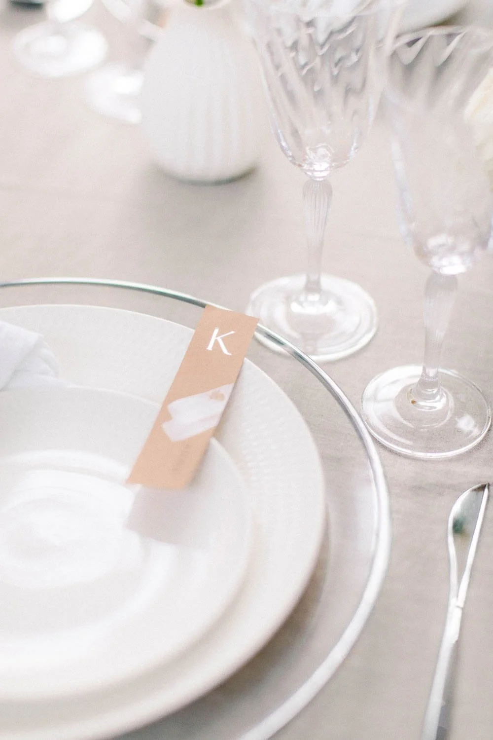 Simple wedding table decor with clean place setting, glass charger plate, linen tablecloth and elegant glassware by de Waay