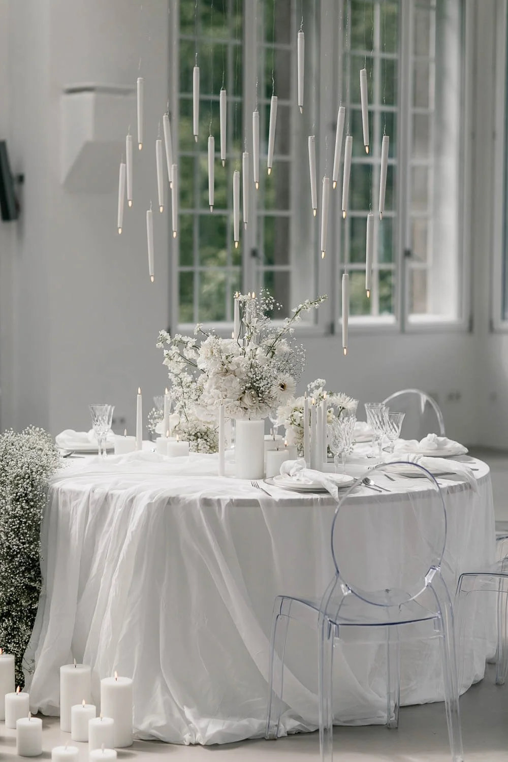 Minimalistische weiße Tischdeko zur Hochzeit mit Ghost Chairs, schlichten Kerzen und moderner All-White-Tafel von de Waay