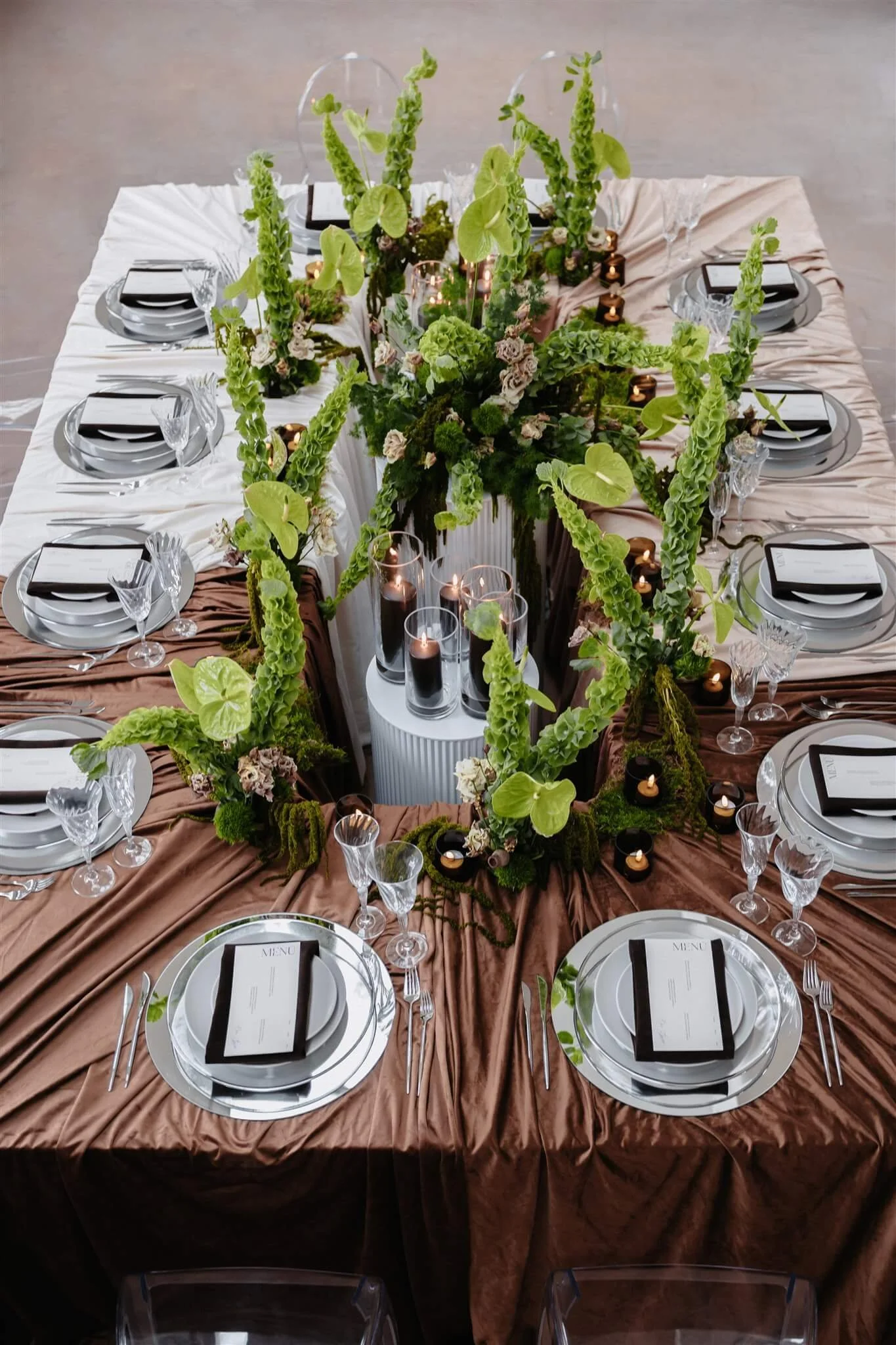 Hochzeitsfarben 2026: moderne Hochzeitstafel mit Tischdecken in verschiedenen Brauntönen wie Caramel, Beige, Nougat und Hot Chocolate von de Waay, grünem Floristikakzenten und natürlicher Tischdekoration von oben gesehen