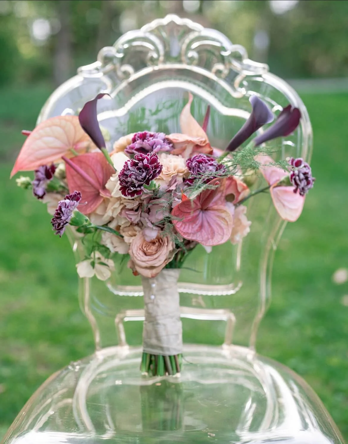 Brautstrauß mit üppiger Frühlingsfloristik auf transparentem Bella Stuhl von de Waay– Beispiel für typische Fehler bei Tischdeko Hochzeit Frühling