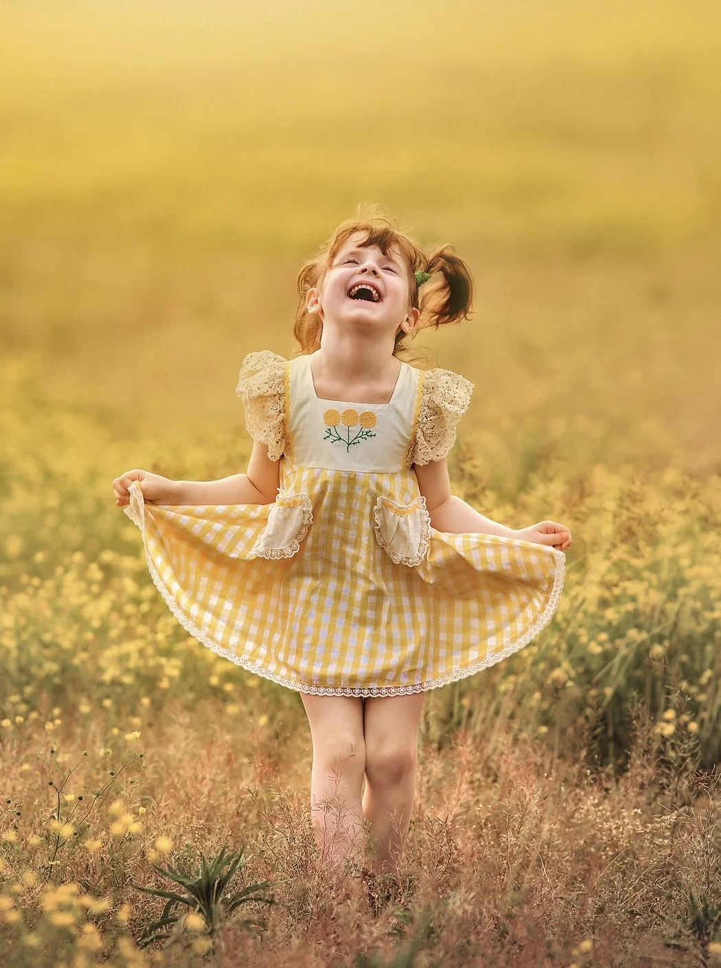 Fine art summer portrait of a child in a yellow dress laughing and looking up during golden hour in New Jersey