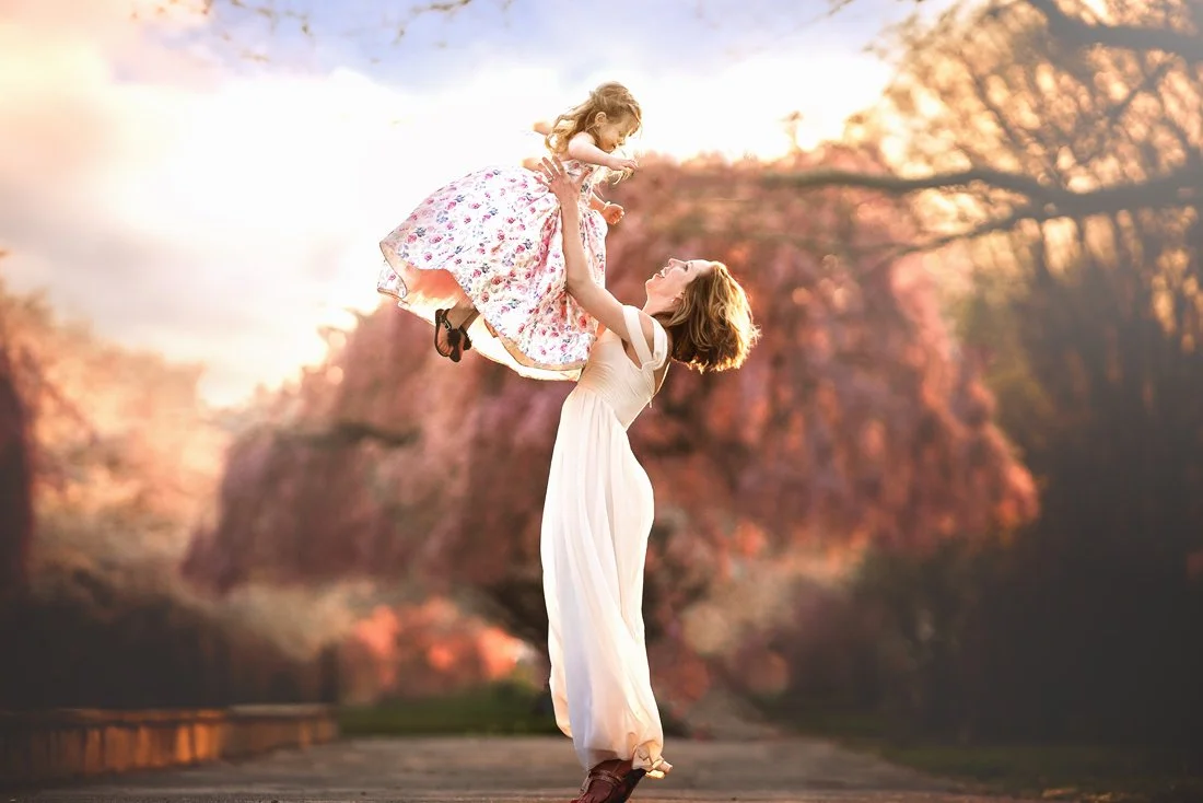 Mother and daughter sharing a quiet spring moment beneath cherry blossoms in Fairmount Park.