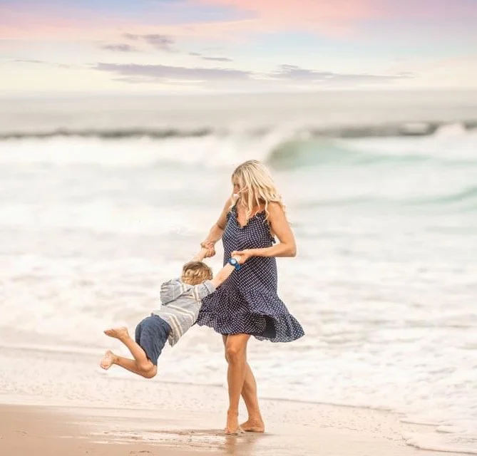 Mother twirling her son during a sunset family photography session in Ocean City New Jersey.