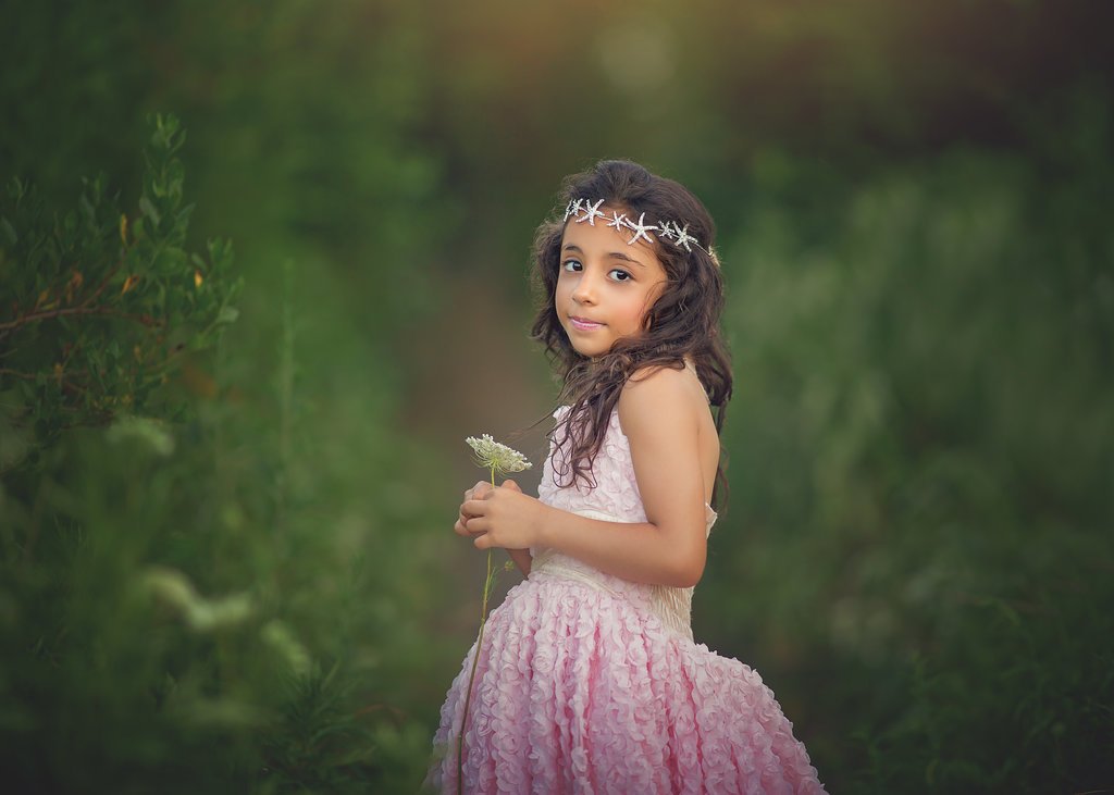 Close-up of a young girl’s joyful expression, holding a seashell on the sandy beach during her Jersey Shore birthday photo session with a Cape May photographer.