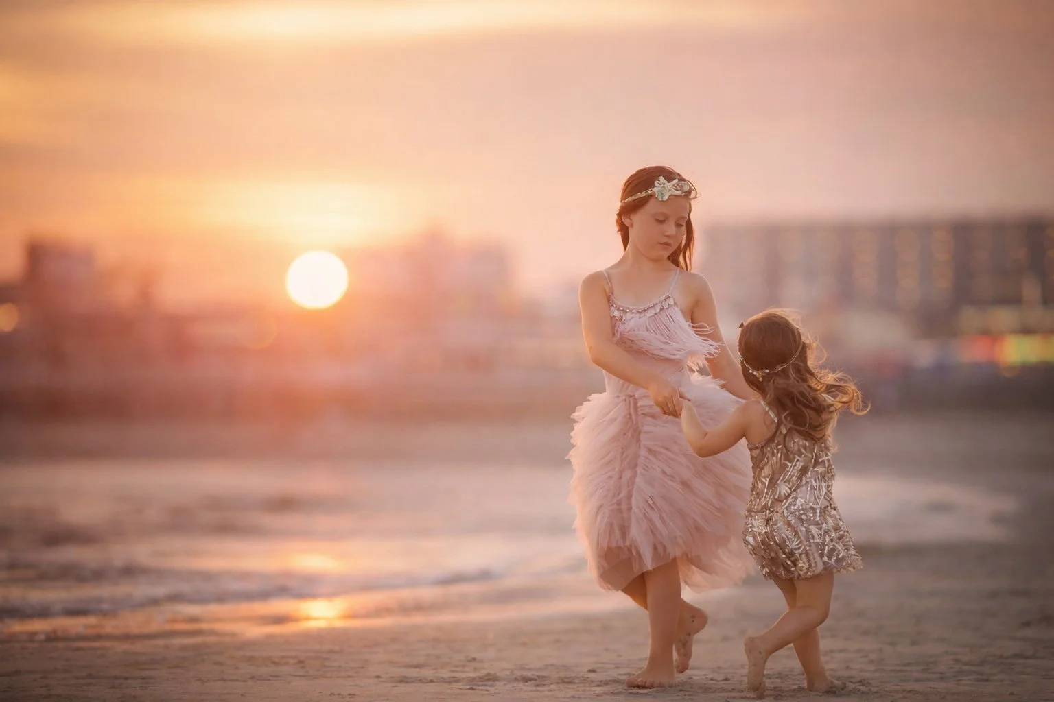 Two sisters holding hands on the beach at sunset during a Jersey Shore portrait session in Wildwood, NJ.