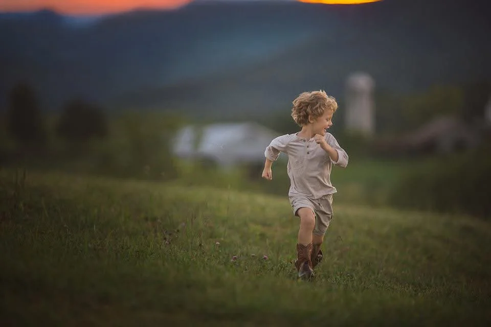 Toddler running freely through a field during a joyful, natural light baby and toddler portrait session in South Jersey.